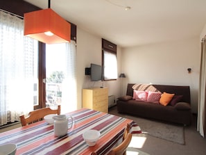 Cozy living space with a dining area and seating area, featuring a table, sofa, and television.