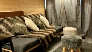 Una habitación acogedora con un sofá, una lámpara y un taburete pequeño.