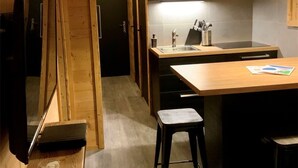 Una cocina compacta con armarios de madera, estufa integrada y una pequeña isla con taburetes.