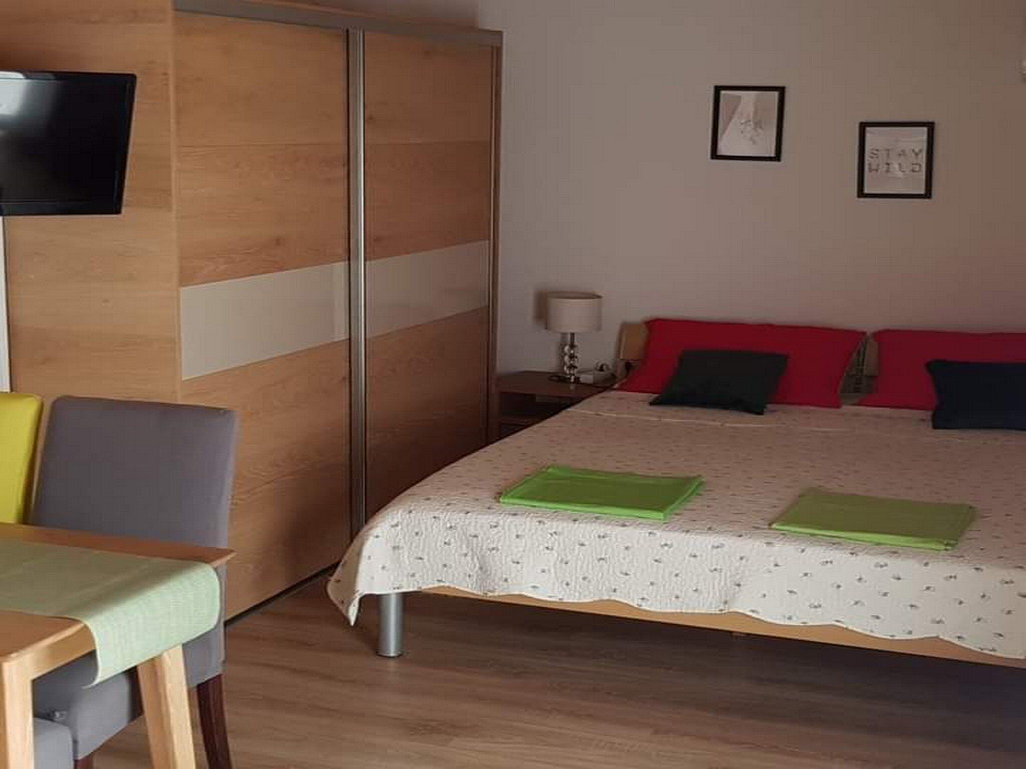 Ein Hotelzimmer mit einem Bett, einem Schreibtisch, einem Sessel, einem Fernseher und zwei gerahmten Bildern an der Wand.