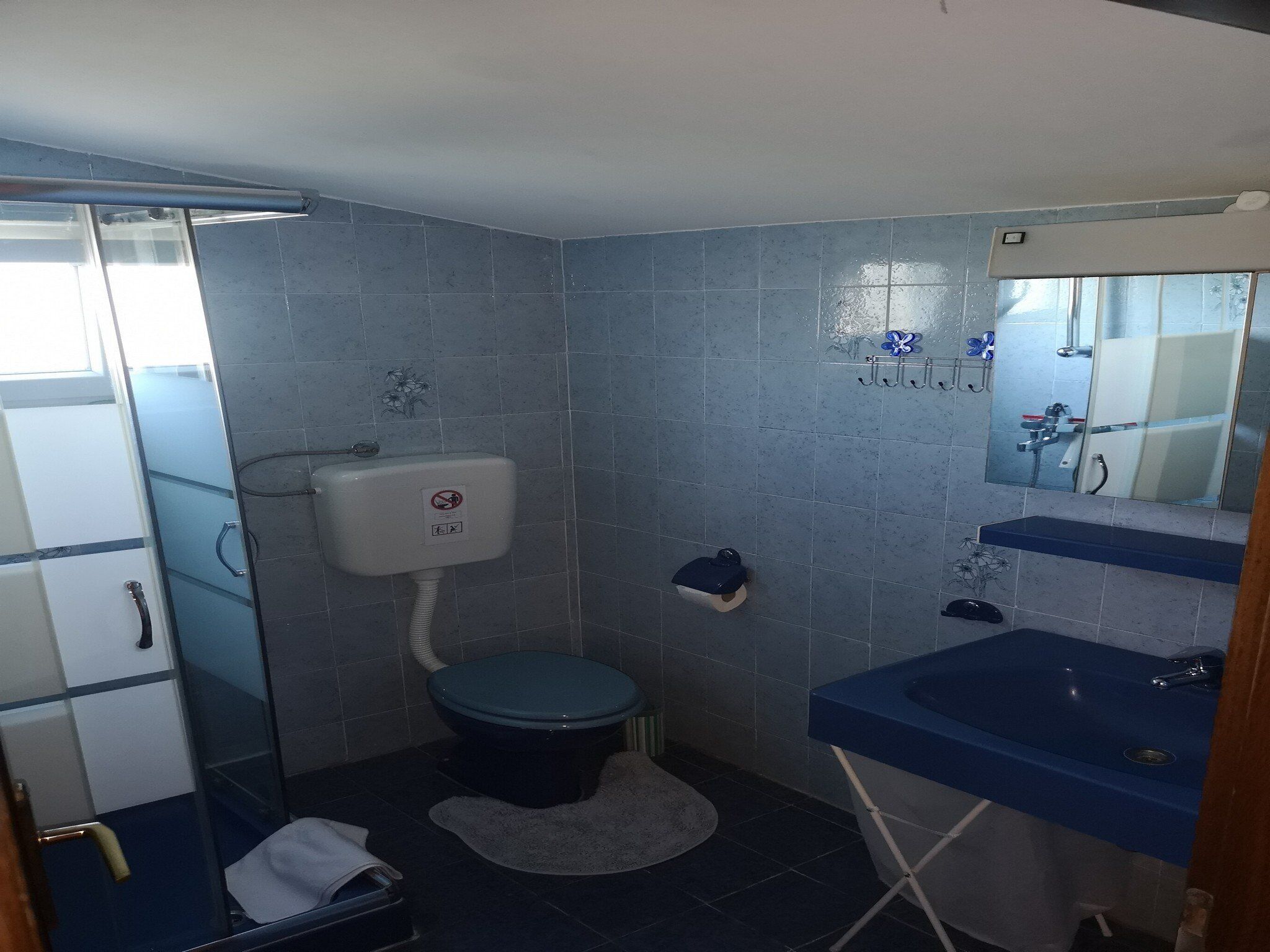 A small bathroom with a toilet, sink, and shower.