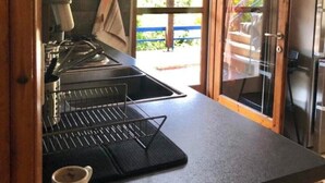 A kitchen with a black countertop, a coffee cup, and a view of the outside. - Elesta 2 Bedroom House (Vourvourou)