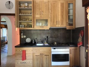 A compact kitchen with wooden cabinets, a stove, and a dishwasher.