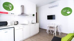 A modern kitchen with a microwave, kettle, sink, and a flat-screen TV.