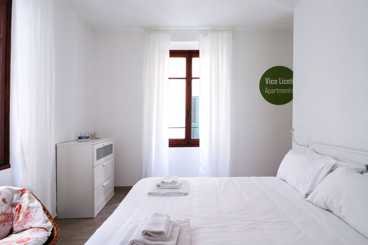 Une chambre à coucher avec un lit, une table de chevet, une chaise et une fenêtre.
