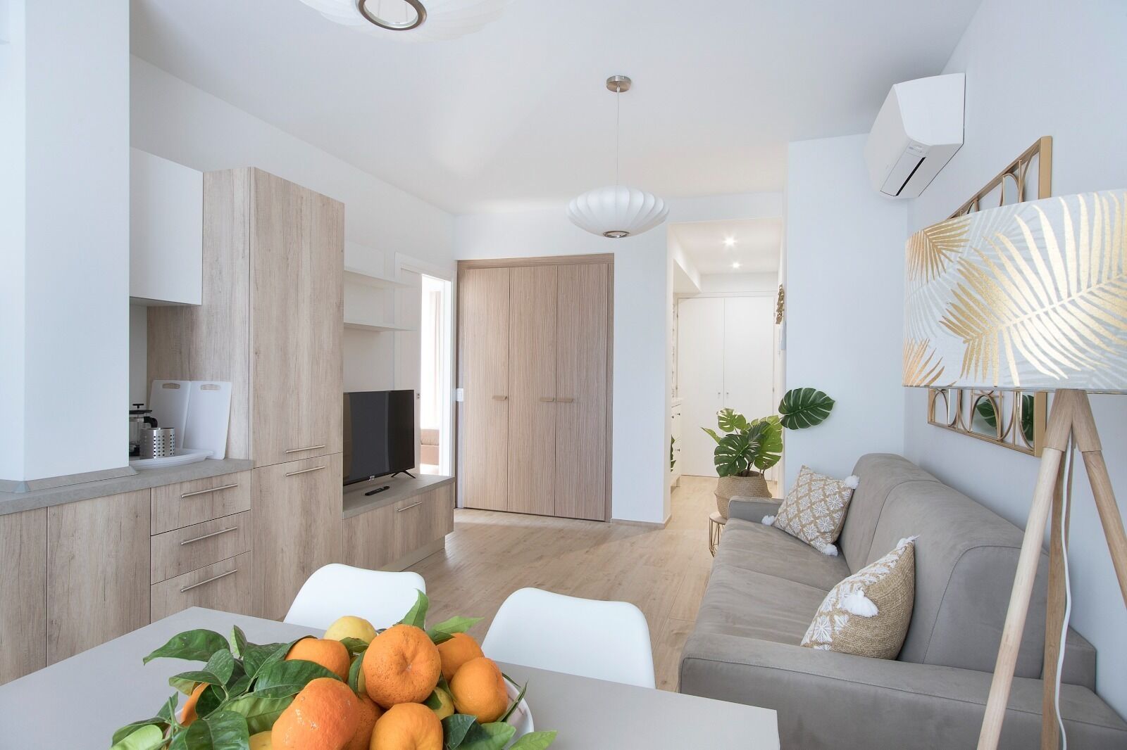 Ein modernes Wohnzimmer mit einer Couch, einem Esstisch mit Obst und einem Fernseher.