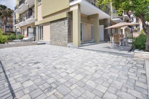 Un moderno edificio de apartamentos con un patio empedrado, mobiliario exterior y fachada de piedra.