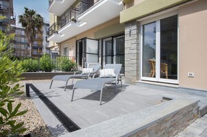 Un patio moderno al aire libre con sillones reclinables y una pared de piedra.