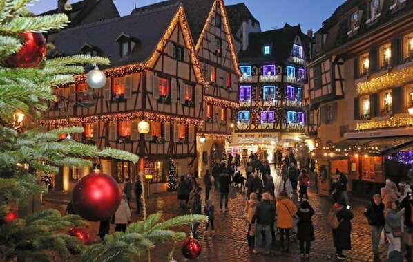 A traditional half-timbered building with a Christmas market in front. - Cozy house with a terrace near the train station (Sélestat)