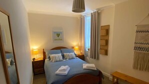 A neatly arranged bedroom with a large bed, bedside lamps, a mirror, and a wall-mounted shelf. - Newburghaprtment/scotland/sleeps 4/firepit/garden (Cupar)