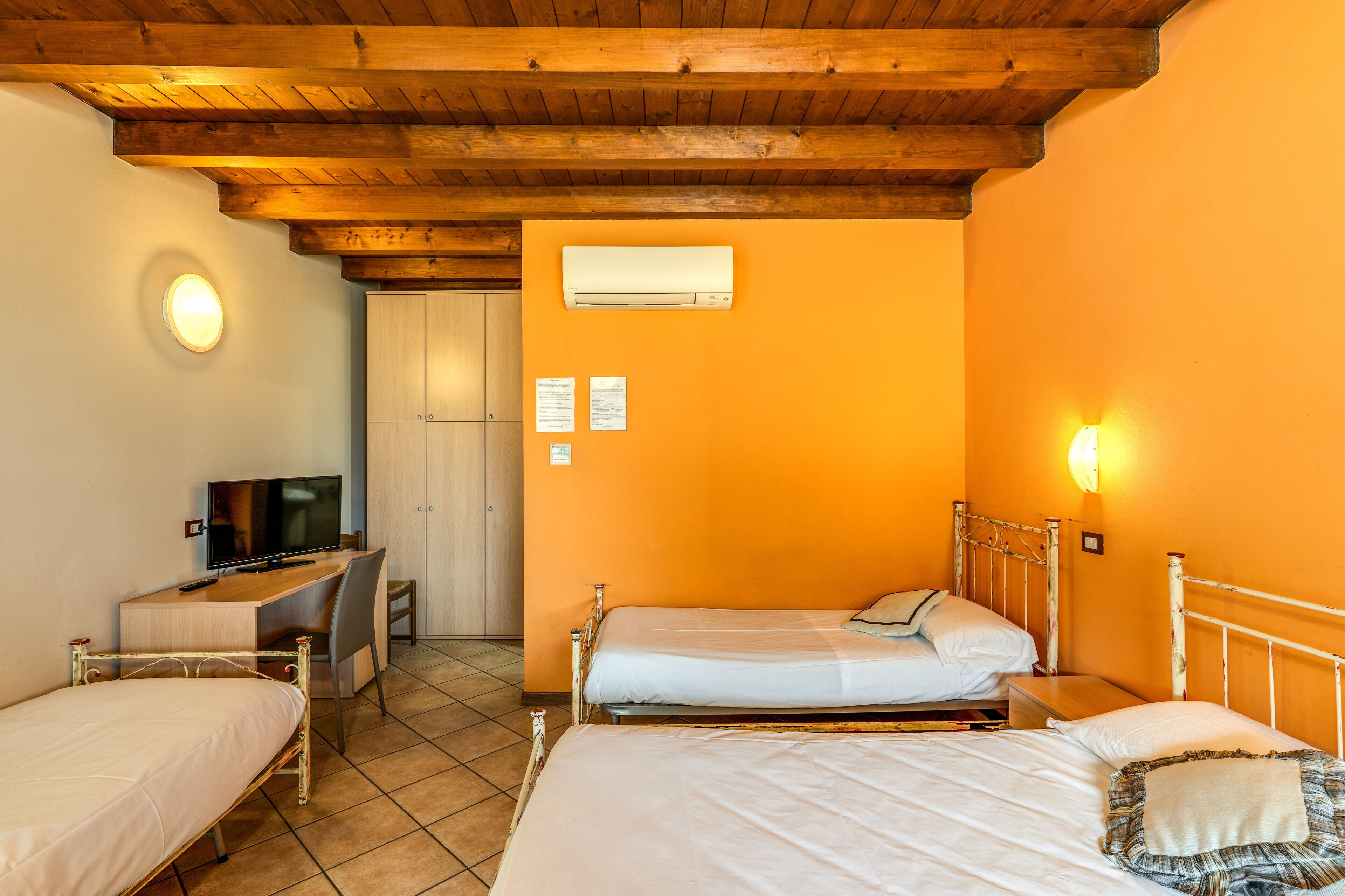 Une chambre avec deux lits, un bureau, une télévision et un appareil de climatisation.