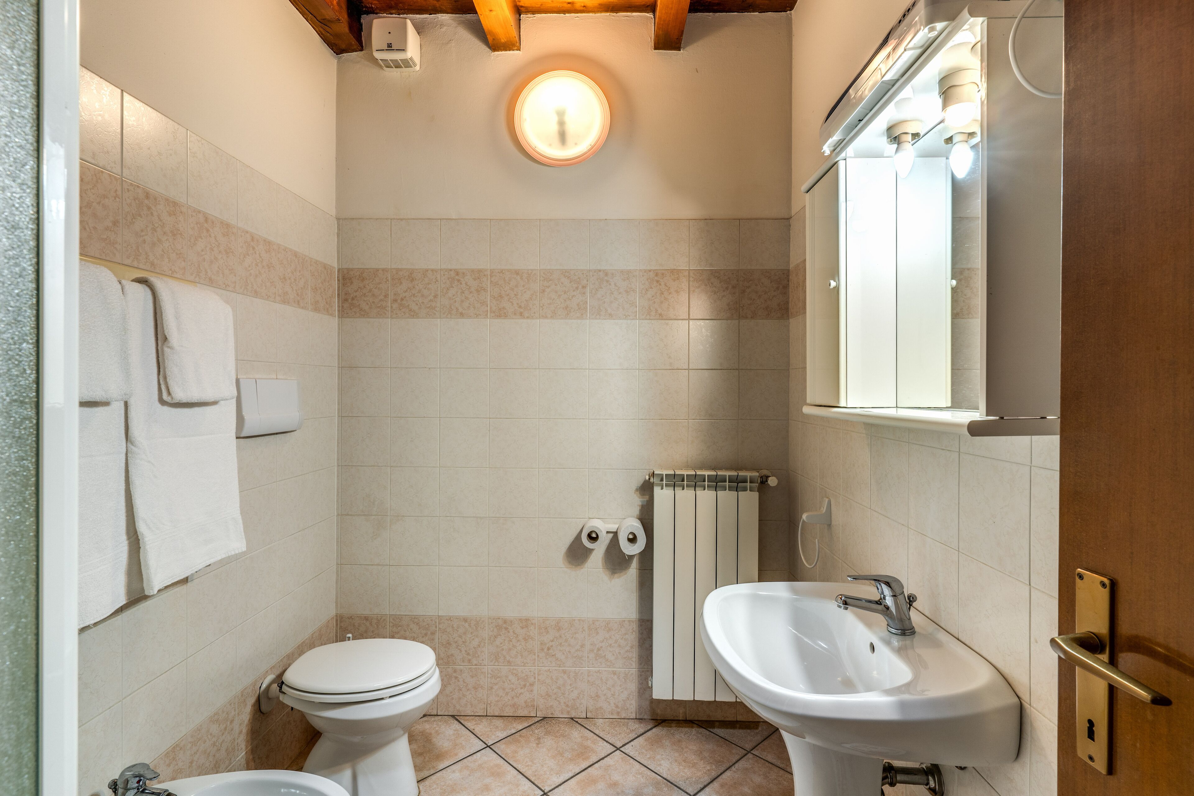Un baño pequeño con inodoro, lavamanos y perchero para toallas.