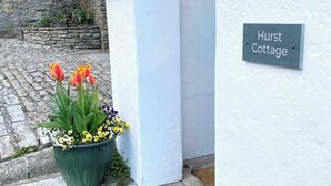 A sign reading "Hurst Cottage" next to a white wall with a stone wall and a flower pot in the foreground. - 2 Bedroom Cottage - Sleeps 4 - Wifi, Fireplace (Sturminster Newton)