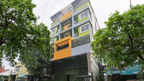A multi-story building with a green and orange facade, a covered entrance, and a parked motorcycle. - Bernbon Condominiuim Manila (Manila)