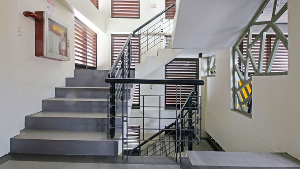 A multi-level interior with a staircase, metal railings, and windows with blinds. - Bernbon Condominiuim Manila (Manila)