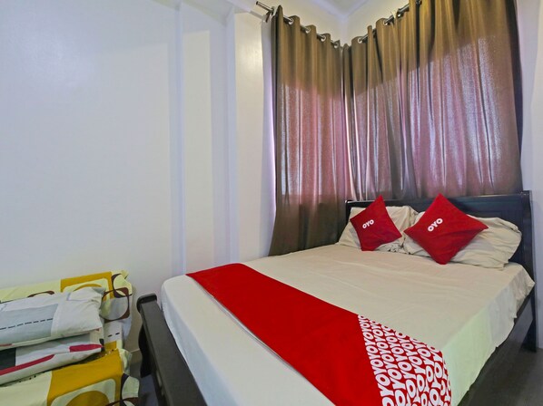 A hotel room with a bed, two red pillows, a red throw, and a yellow trolley with towels. - Bernbon Condominiuim Manila (Manila)
