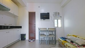 A compact room with a kitchenette, a bed, a TV, and a window. - Bernbon Condominiuim Manila (Manila)