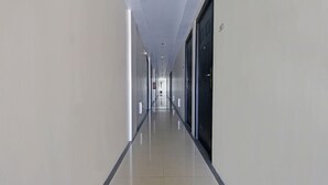 A long, narrow hallway with a reflective floor, doors on both sides, and a ceiling with recessed lighting. - Bernbon Condominiuim Manila (Manila)