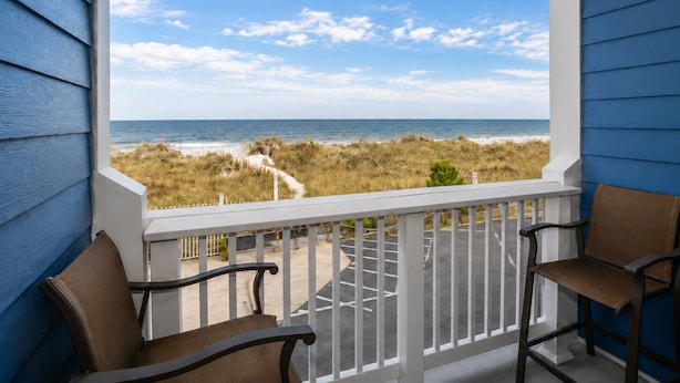 A balcony with a view of the beach and ocean.