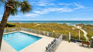 A swimming pool with a view of the ocean and beach.