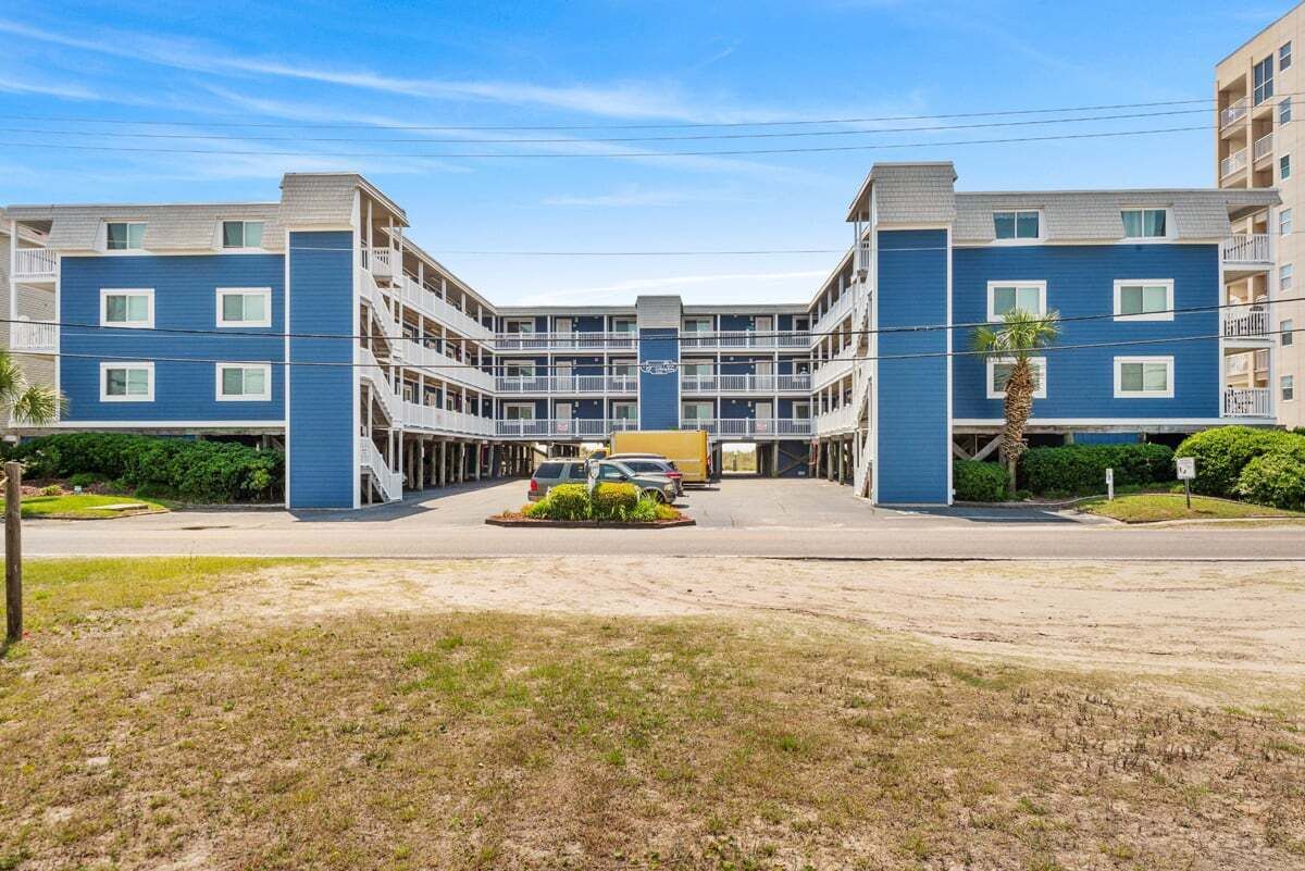 Een meerlaags hotel met een centrale binnenplaats, balkons en een parkeerplaats.