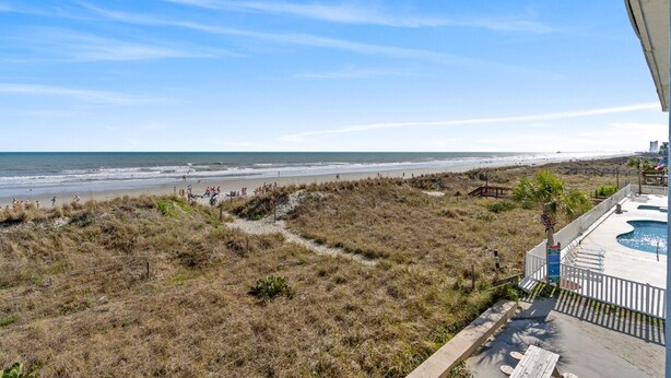 A beach view from a balcony with a pool and a sandy area with people. - Pet-Friendly Oceanfront 2-BR on Top/3rd Floor – Stunning Cherry Grove Beach Views - Blue Mist 302 (North Myrtle Beach)