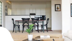 Una cocina moderna con armarios blancos, una mesa de comedor con sillas y una planta en maceta.