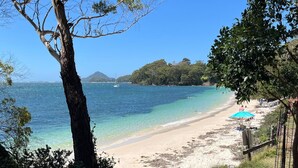 Una playa con agua cristalina, una orilla arenosa y una montaña al fondo.