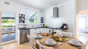 Eine moderne Küche mit weißen Schränken, einem Edelstahl-Geschirrspüler und einem Essbereich, der für eine Mahlzeit gedeckt ist.