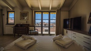 Une chambre d’hôtel équipée d’un lit, d’une télévision, d’un bureau, d’une chaise et offrant une vue sur la ville grâce à de grandes fenêtres.