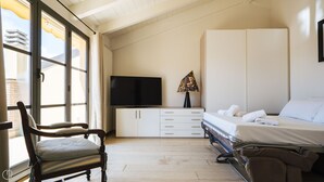 Une chambre à coucher avec un lit, une télévision, une chaise et une armoire.