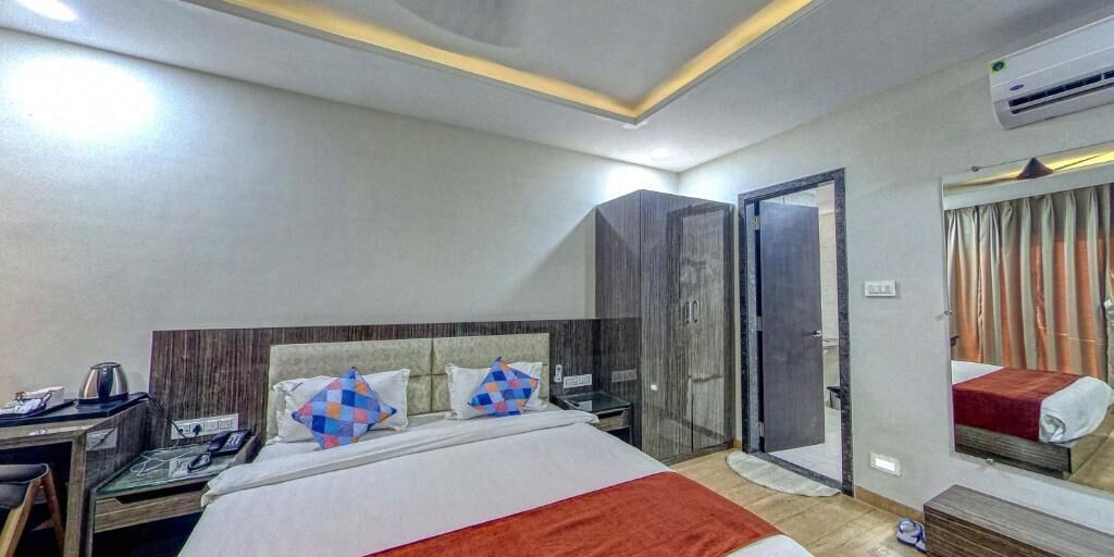A hotel room with a bed, a desk, a chair, a wardrobe, and a bathroom door.