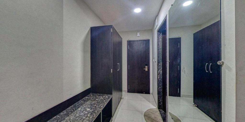 A hallway with dark wooden doors, a bench, and a tiled floor.