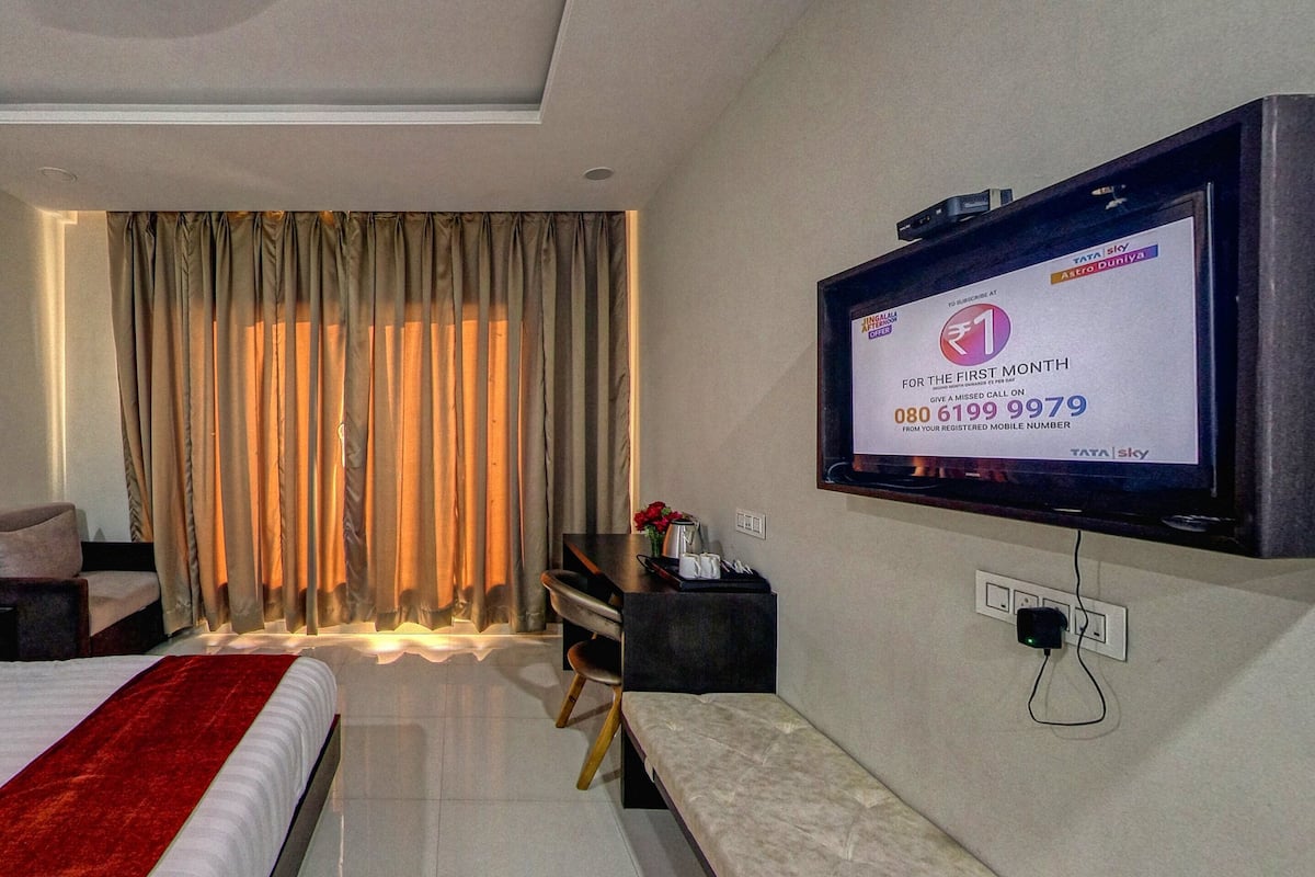 A hotel room with a bed, a desk, a television, and a window with curtains.