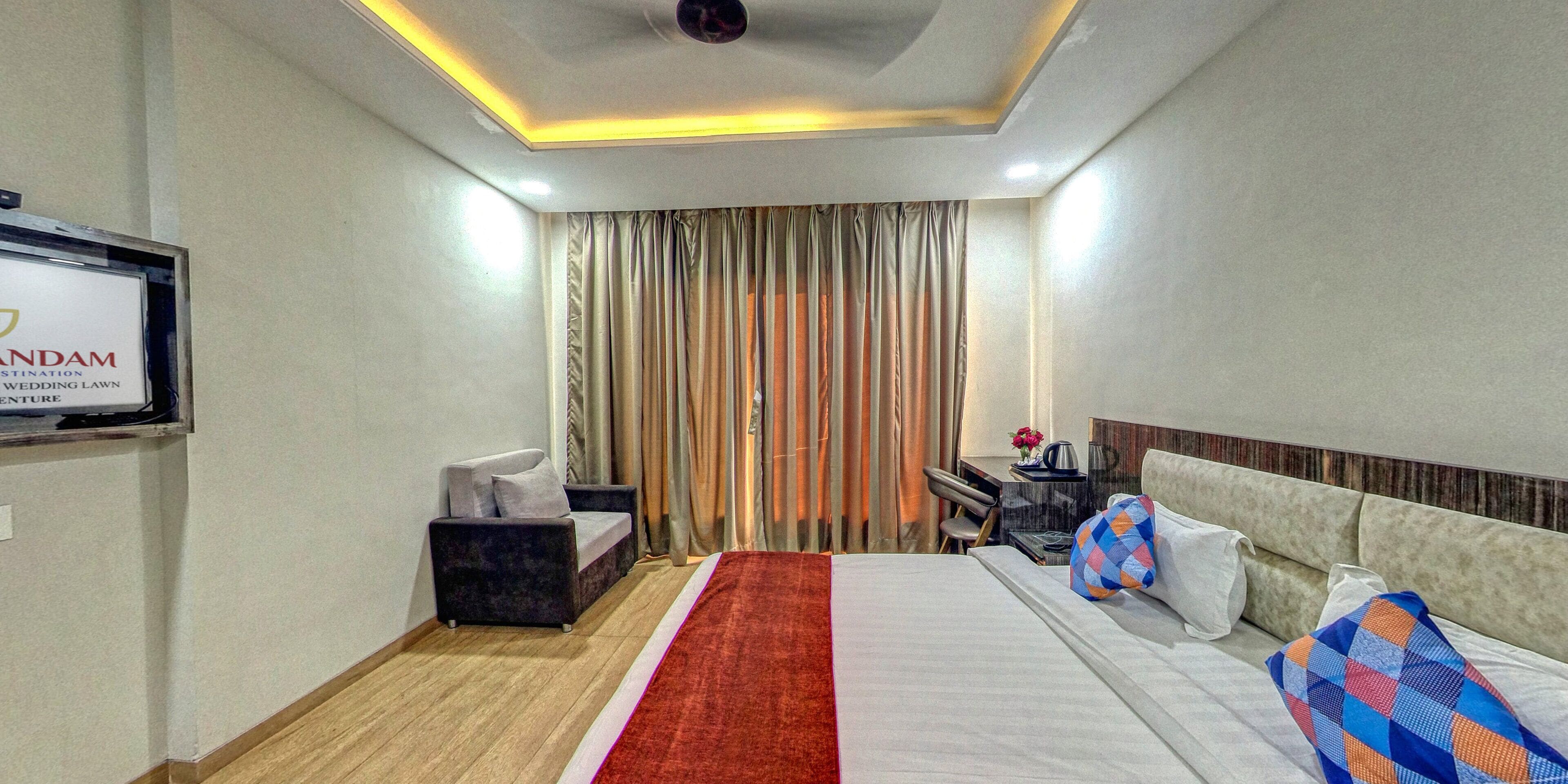 A hotel room with a bed, a desk, a chair, a TV, and curtains.