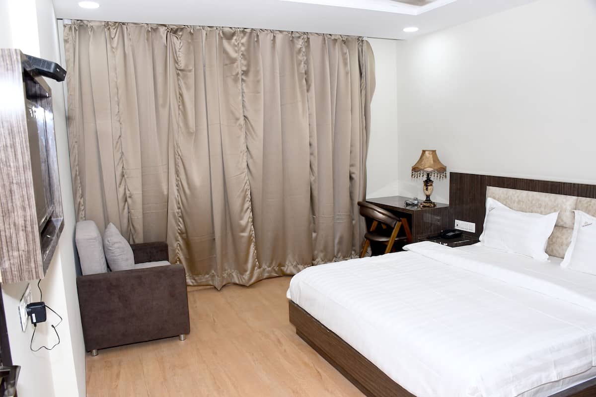 A hotel room with a bed, a desk, a chair, and a curtain.