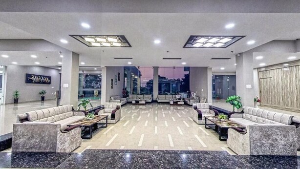 A spacious lobby with a central seating area, large windows, and a modern design. - The Aanandam Hotel Resort (Itarsi)