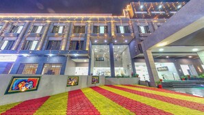 A modern building with a geometric facade, large windows, and a brightly lit entrance area with a patterned floor. - The Aanandam Hotel Resort (Itarsi)