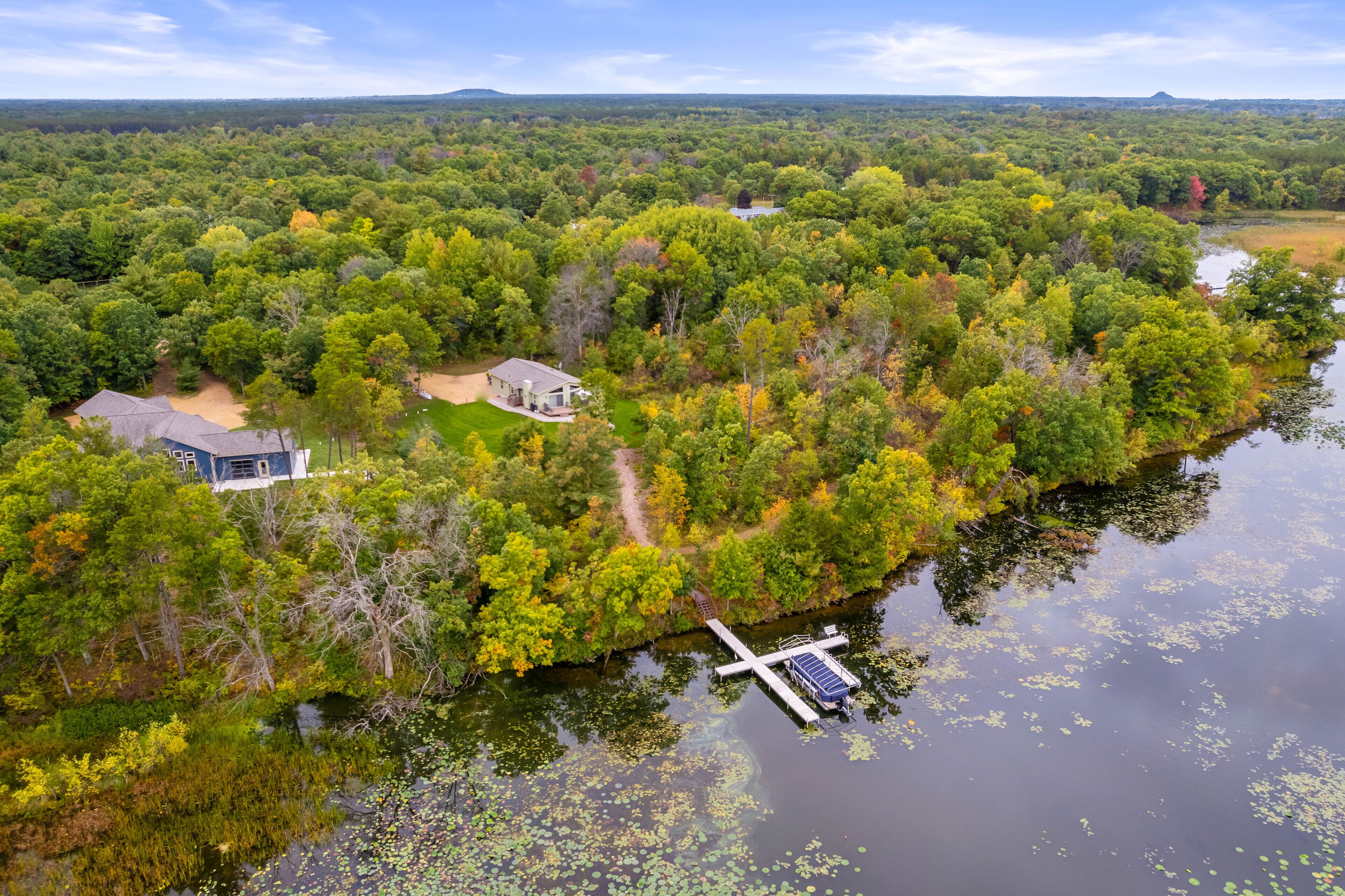 Ein Haus, umgeben von dichtem Wald und einem See mit einer Anlegestelle.