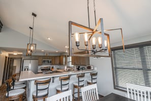 A modern kitchen with a central island, bar stools, and pendant lighting.