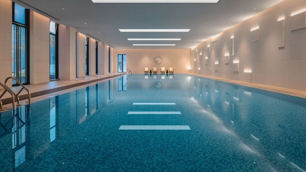 Une piscine intérieure moderne, dotée de couloirs bien délimités, de grandes fenêtres et d’un éclairage contemporain.