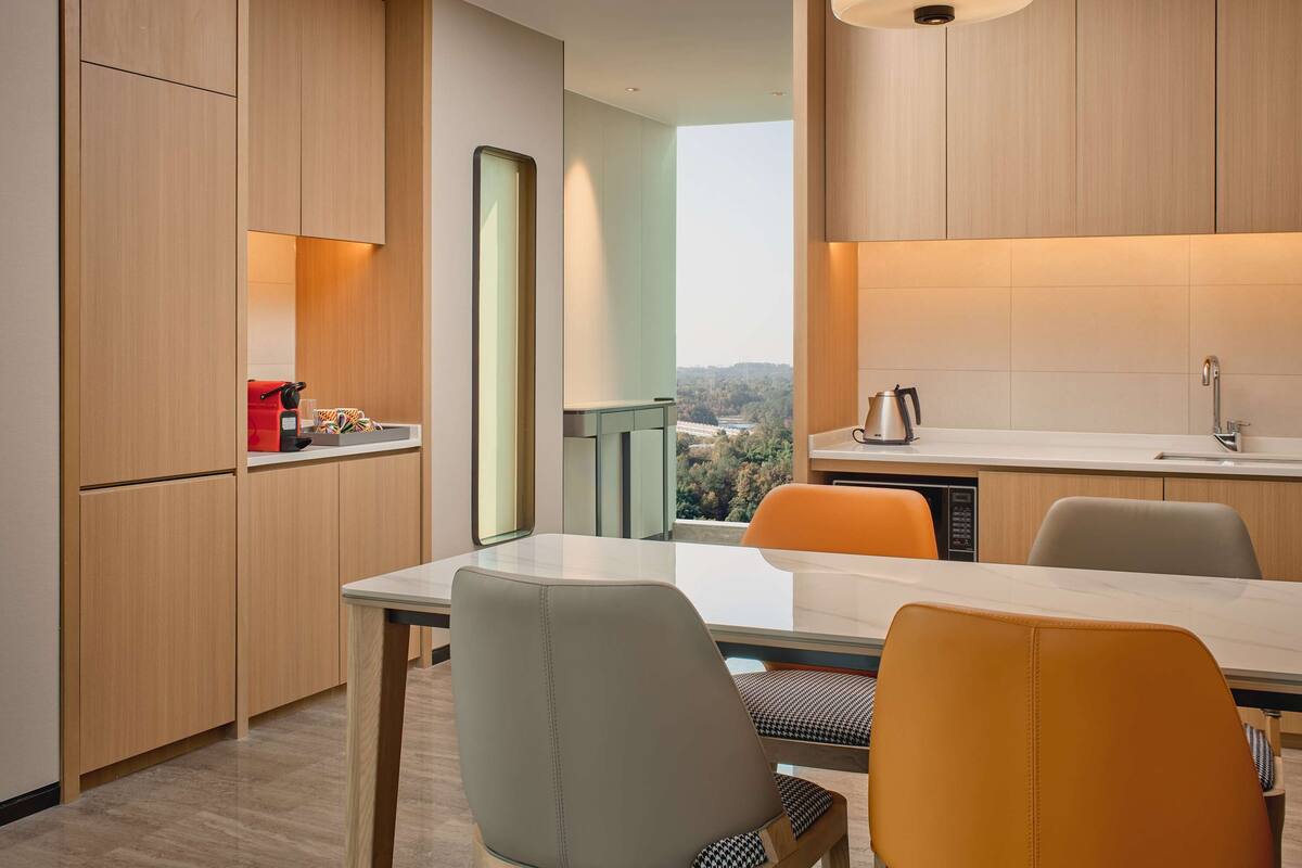 A modern kitchen with wooden cabinets, a dining table, and chairs.