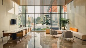 Un hall d’entrée spacieux, doté d’un long comptoir de réception, de coins salons confortables et de grandes fenêtres offrant une vue sur l’extérieur.