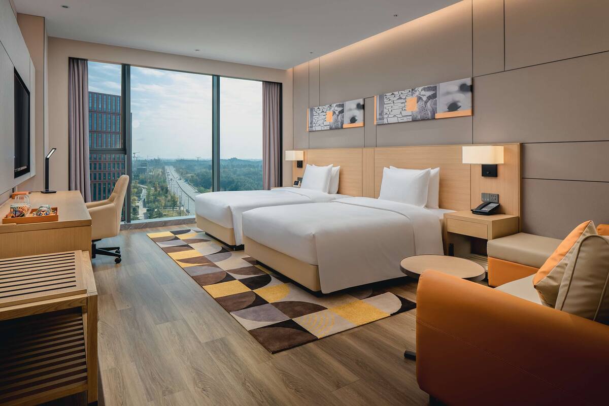 A modern hotel room with a large bed, two bedside tables, a desk, and a chair.