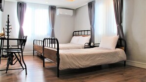 A hotel room with two single beds, a wooden floor, a desk with a chair, and a window with curtains. - Mt Seorak the East Sea and Hot spring (Sokcho)
