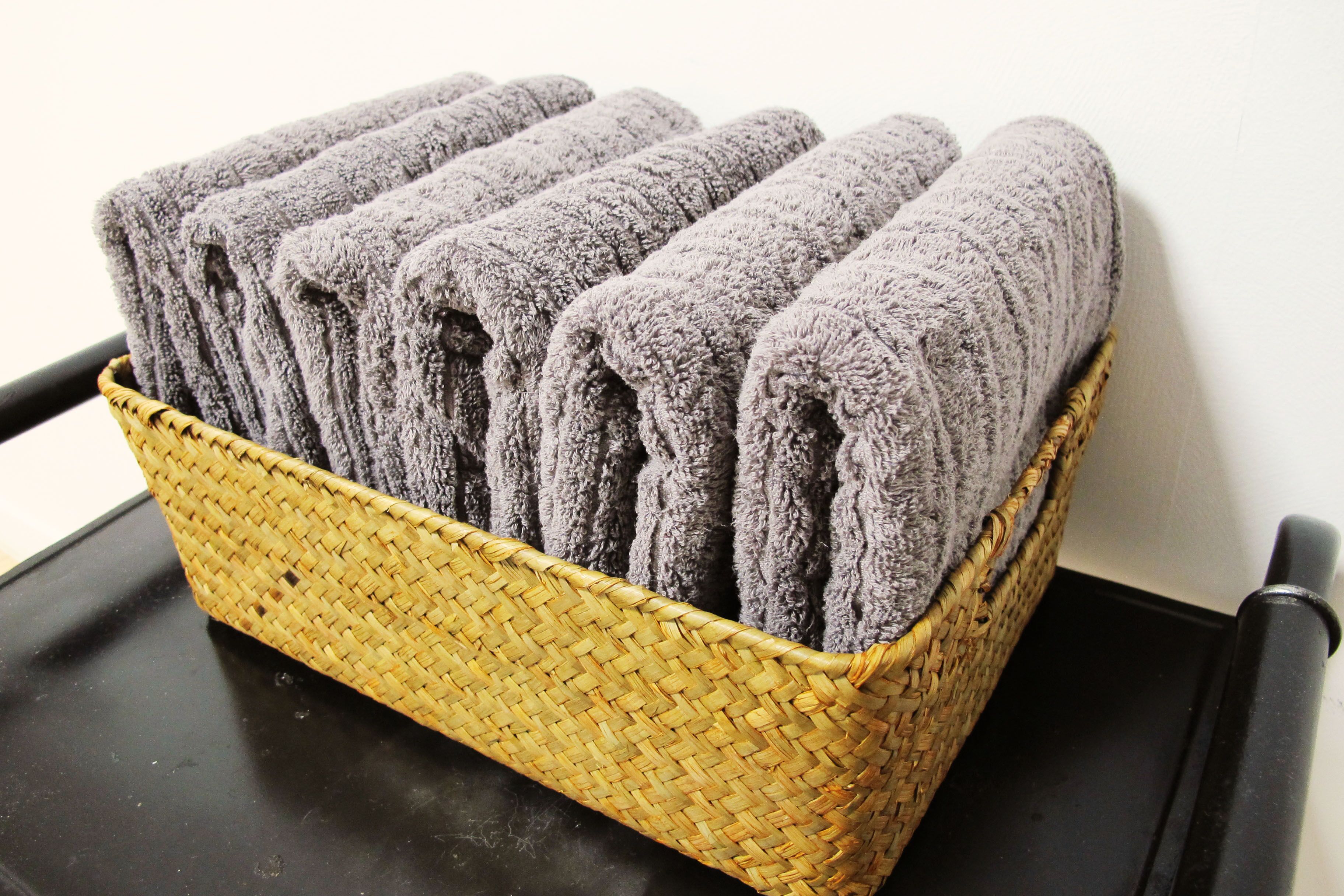 A woven basket containing neatly folded towels.