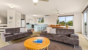 A modern living room with two grey sofas, a wooden coffee table, and a kitchen in the background. - Views on Bayview - in Cowes (Cowes)