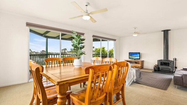 A spacious living area with a wooden dining table, chairs, a TV, and a fireplace. - Views on Bayview - in Cowes (Cowes)