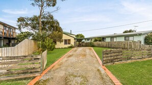 A residential property with a gravel driveway, wooden fences, and a lawn. - Views on Bayview - in Cowes (Cowes)