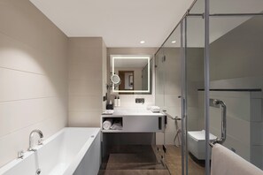 A modern bathroom with a bathtub, a glass shower enclosure, and a vanity with a mirror. - voco Amritsar by IHG (Amritsar)